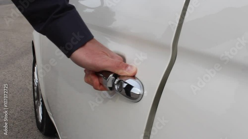 Hand of white man grabs door handle of white car first then opening the door gently.