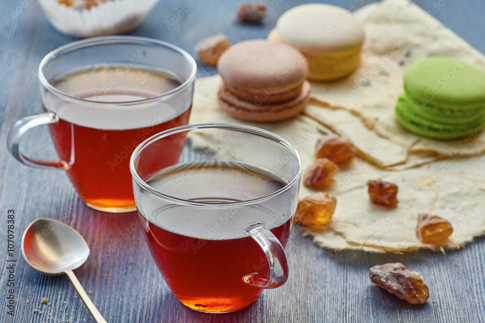 Two glass cups of black tea and colorful macaroons Two glass cups of black tea and colorful macaroons