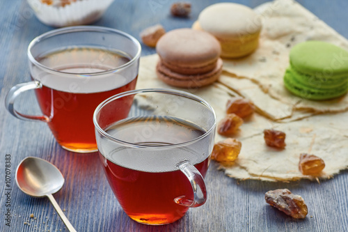 Two glass cups of black tea and colorful macaroons