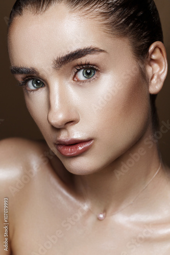 Strobing or Highlighting makeup. Closeup portrait of beautiful girl with strobing highlighter powder. Nice Glow. Perfect retouch. Studio photo beige background. Wet body effect photo