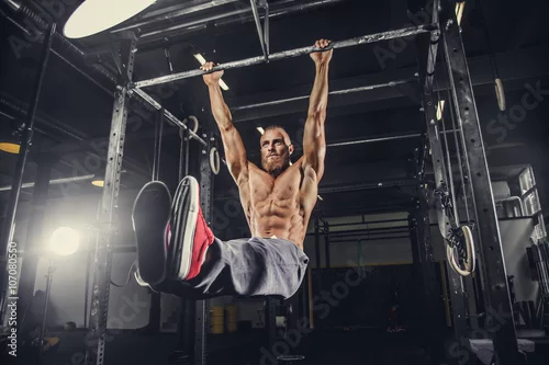 Obraz Mężczyzna robi ćwiczenia brzucha na poziomym pasku.