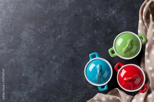 Colorful saucepans on stone table