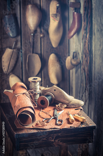 Aged cobbler workplace with tools, shoes and leather photo