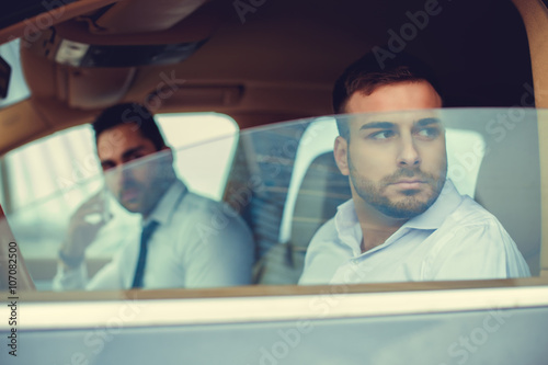 Two guys in a white shirts in the car.