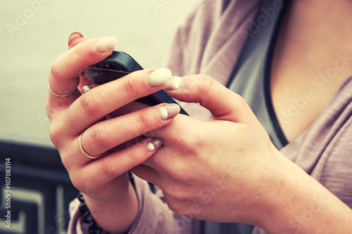 Hands of young woman holding smartphone and texting, vintage color, instagram-like filter