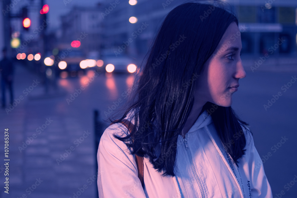 Young woman against a night city lights. Defocused carlights on background. Colorized. Instagram-like filter. Young woman against a night city lights. Defocused carlights on background. Colorized. Instagram-like filter.
