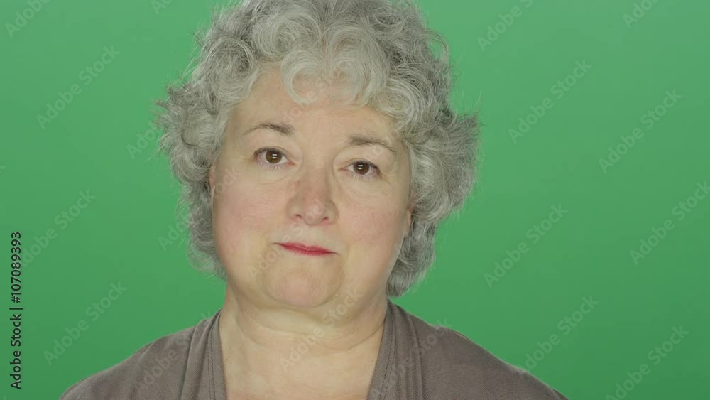 Older woman candidly smiling, on a green screen studio background 