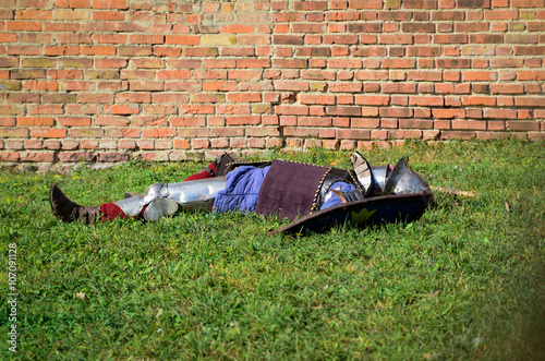 Medieval knight lying on the grass. Outdoor photo in vintage style