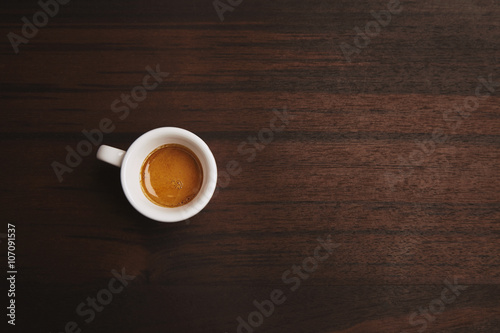 Top view of perfect espresso in small white ceramic cup on red wooden table in cafe shop  isolated on side