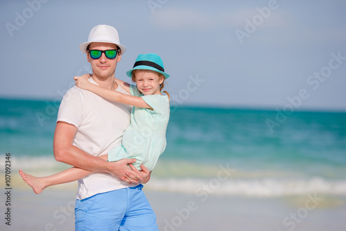 Happy father and his adorable little daughter at tropical beach having fun