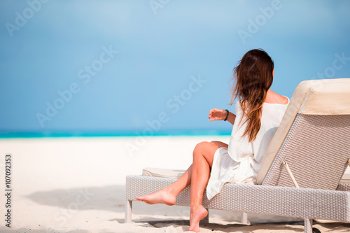 Young woman on lounger with mobile phone at the beach