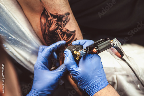 master tattoo artist with a beard makes gloves tattoo on hand men