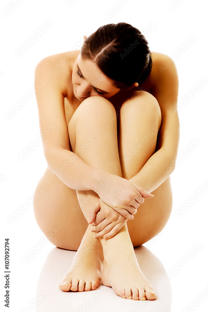 Naklejka premium Attractive sad nude woman sitting holding herself