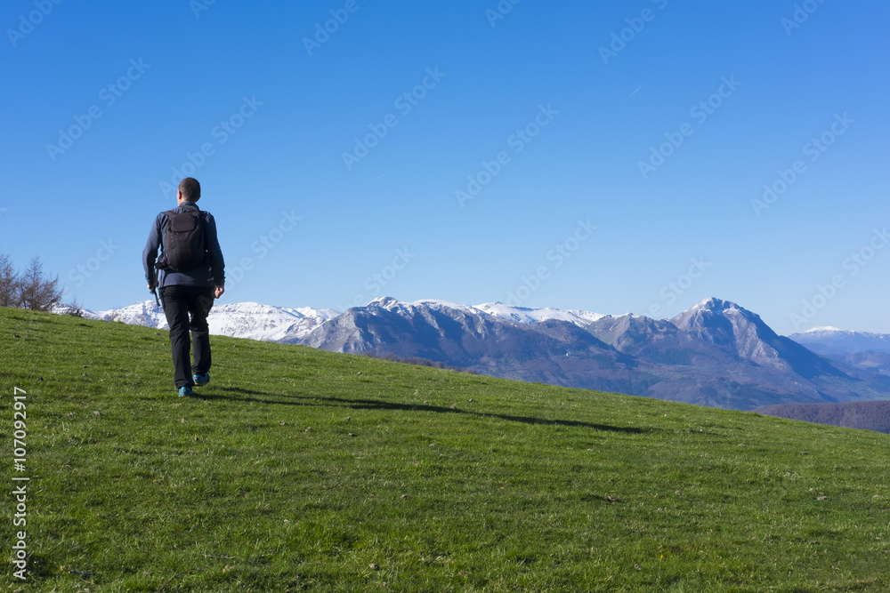 Man playing sports going to the mountain top by green meadow.