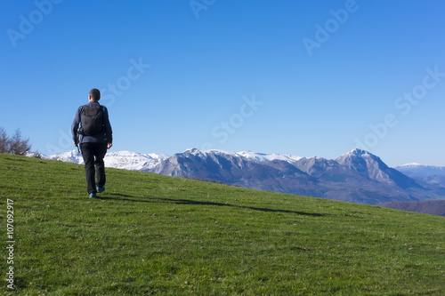 Man playing sports going to the mountain top by green meadow.