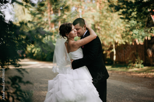 Canvastavla Elegant young happy wedding couple is sitting at green grass on