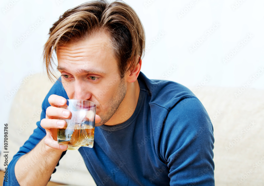 Drunk man sitting on couch and drinking whiskey Drunk man sitting on couch and drinking whiskey