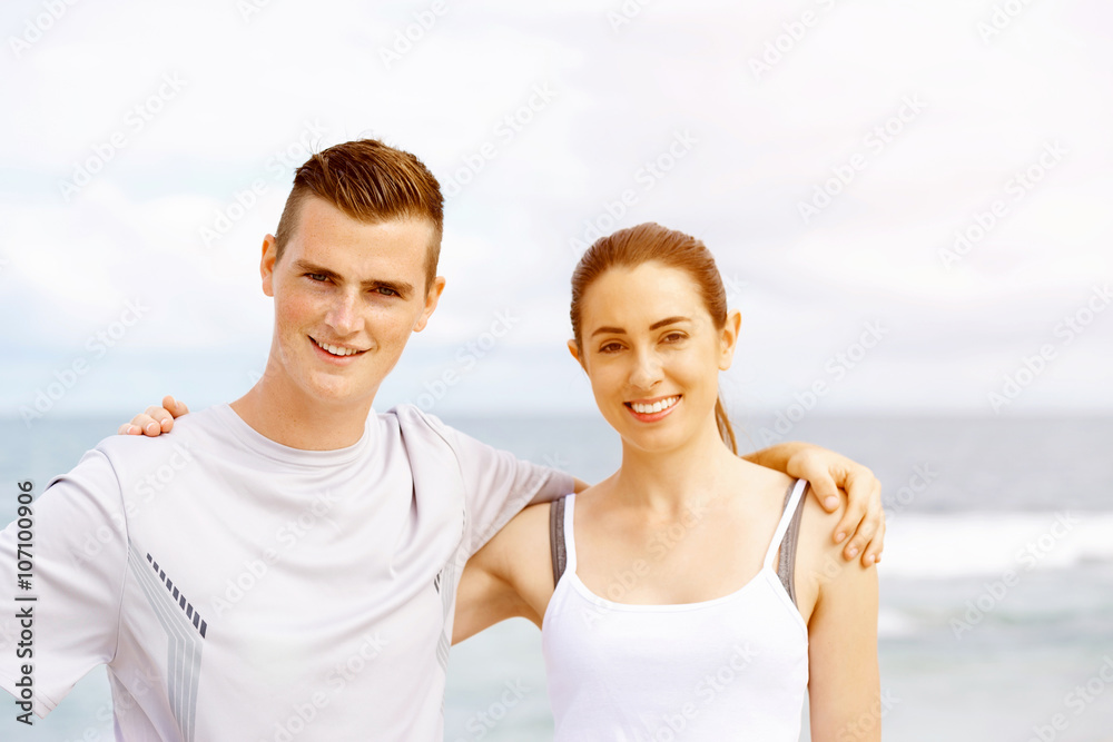 Young couple looking at camera while standing on beach Young couple looking at camera while standing on beach