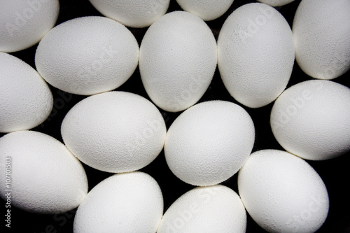 White eggs make a geometric pattern in a pot of boiling water against a black background