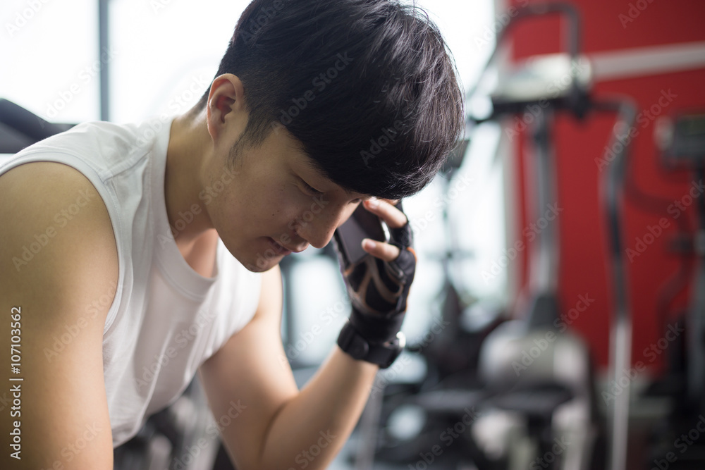 young handsome asian man using smart phone in modern gym young handsome asian man using smart phone in modern gym