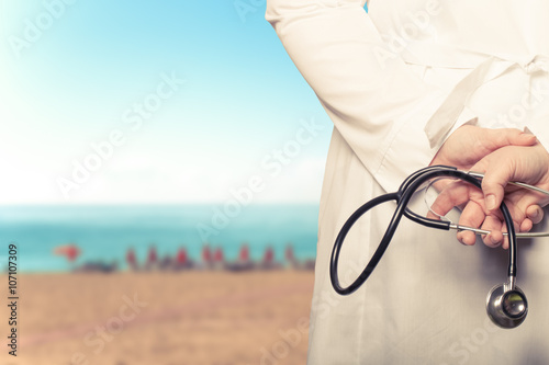 The doctor put his hands with stethoscope behind his back on a b