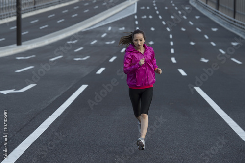 Women are running in the middle of the road wearing a sportswear