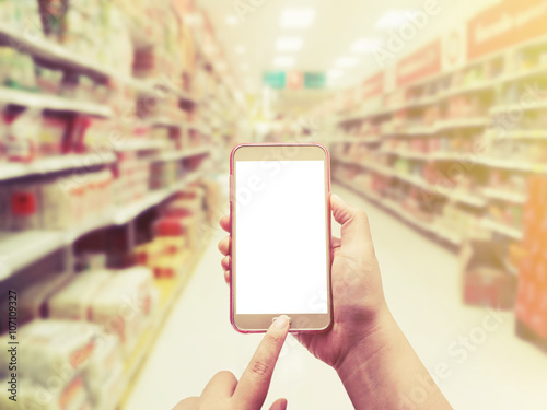 Hand with smartphone on blurred in department store background