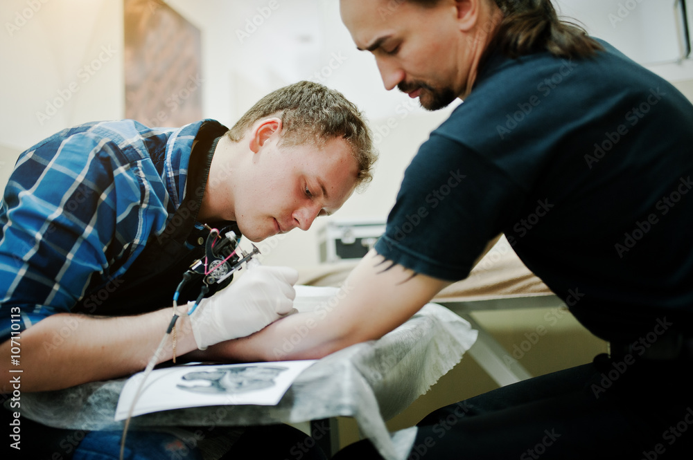 Tattoo master make tattoo for rocker man at tattoo salon Tattoo master make tattoo for rocker man at tattoo salon