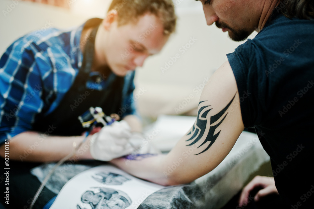 Tattoo master make tattoo for rocker man at tattoo salon Tattoo master make tattoo for rocker man at tattoo salon