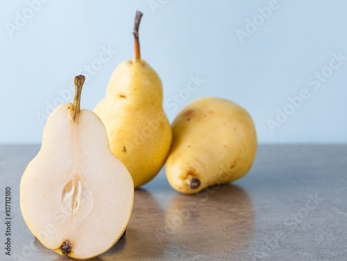 Whole and halved yellow Corella pears with copy space