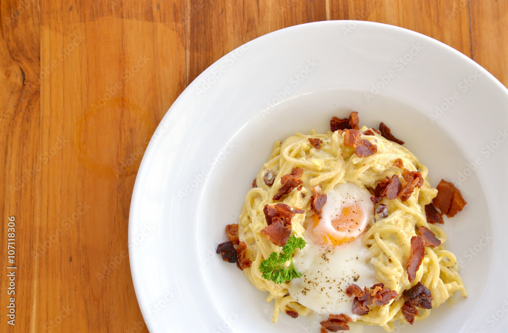 Spaghetti carbonara with crispy bacon and egg on white plate Spaghetti carbonara with crispy bacon and egg on white plate