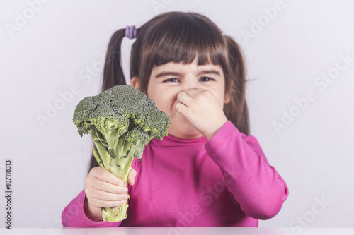 Little girl making a funny face refusing to eat her vegetables