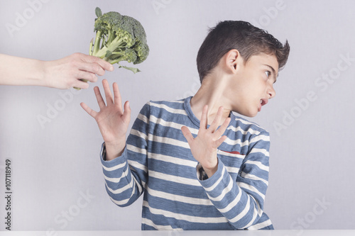 Little boy refusing to eat his vegetables photo