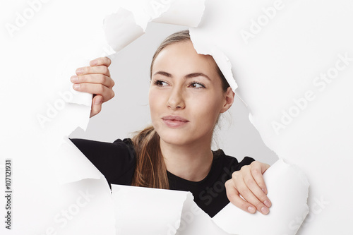 Beautiful woman looking through torn paper