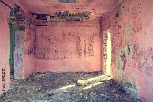Old and abandoned pink room with bad rooftop and light coming through the door