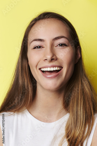 Smiling brown eyed girl in yellow studio