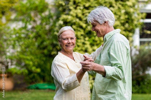 Smiling senior woman with man dancing in yard