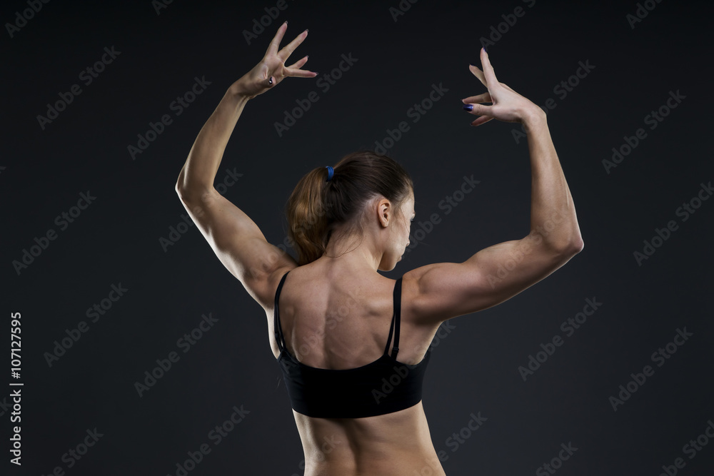 Obraz premium Attractive fitness woman on gray background in studio. Muscular back close-up