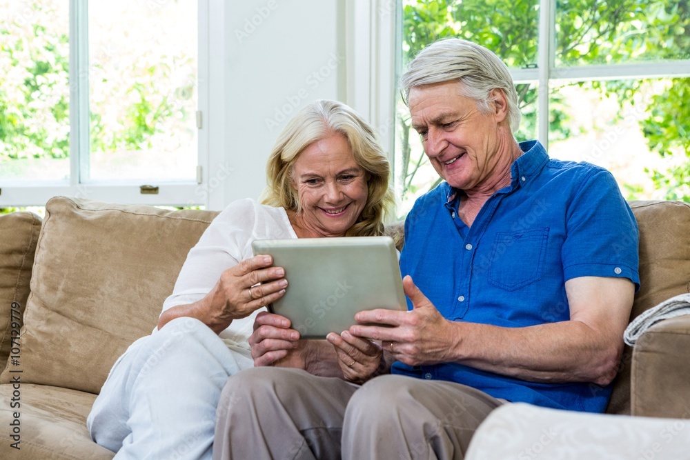 Senior couplHappy senior couple using digital tablet at home Senior couplHappy senior couple using digital tablet at home