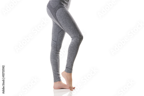 Close up side sexy view of woman legs stretching the muscles of the foot in gray sports thermal underwear with pattern.