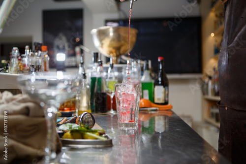 Bartender coocks cocktail behind a bar counter