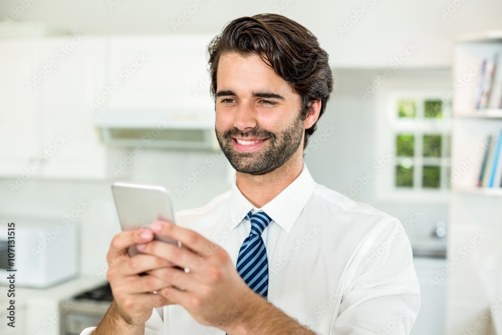 Smiling businessman using cellphone in kitchen Smiling businessman using cellphone in kitchen