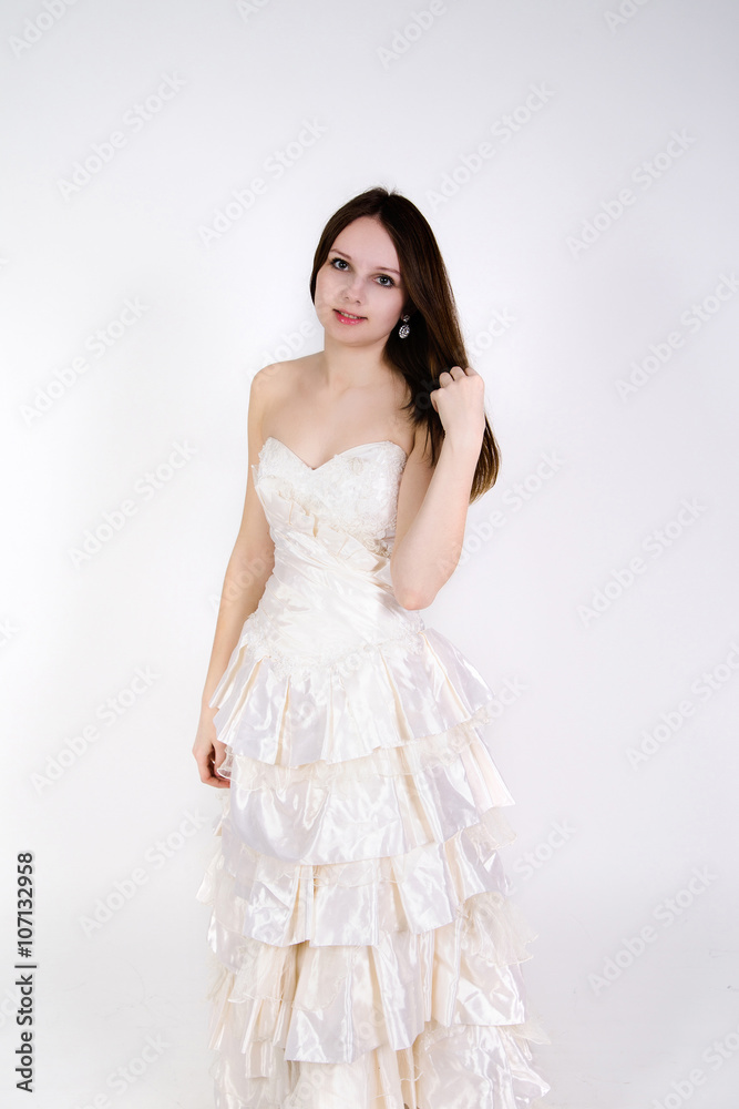 The beautiful young woman in a wedding dress on a white backgrou The beautiful young woman in a wedding dress on a white backgrou