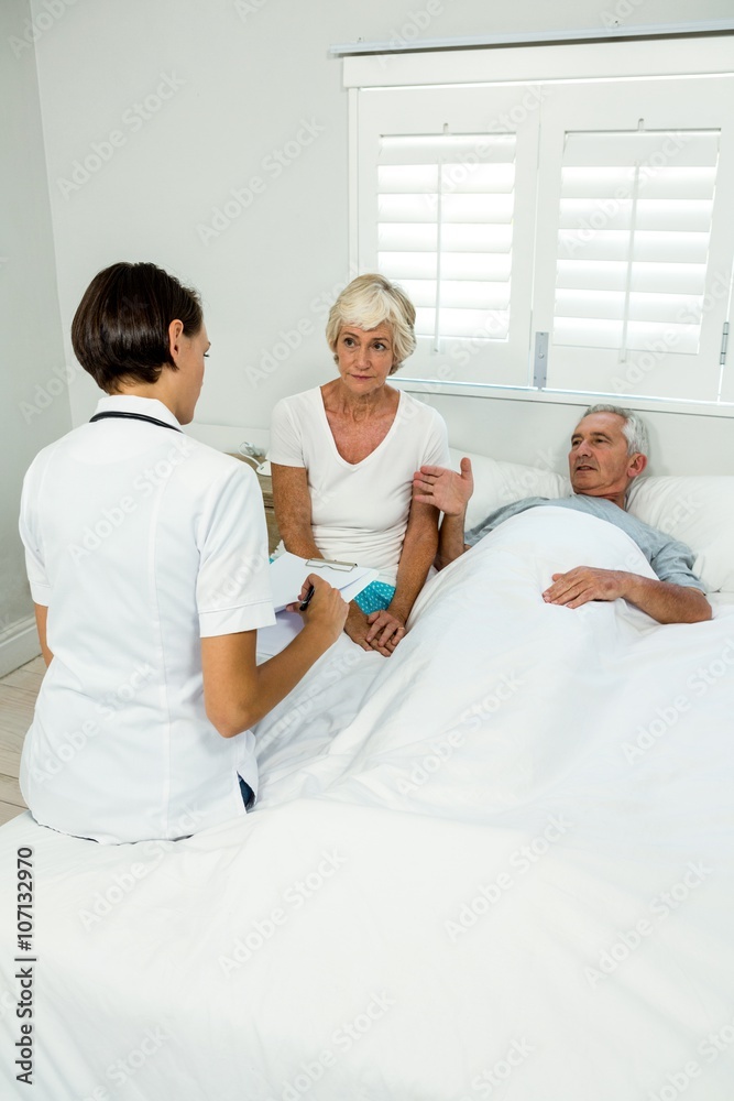 Obraz premium Female caregiver with senior couple at home