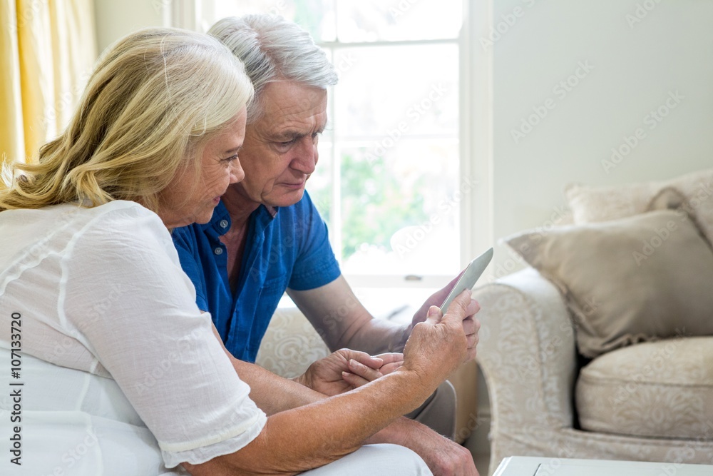Senior couple using digital tablet while sitting at home