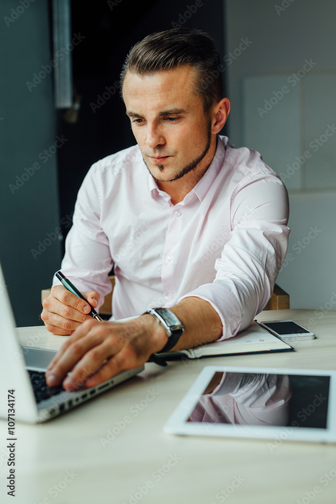 Young man sitting in cafe and adding new meeting in his calendar Young man sitting in cafe and adding new meeting in his calendar