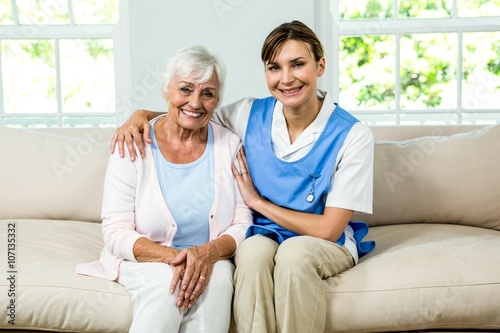 Portrait of smiling nurse with senior woman at home