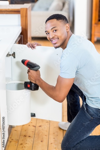 Man drilling a hole inside the cabinet
