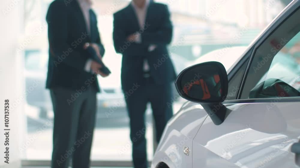 Salesman talking with customer in car dealership