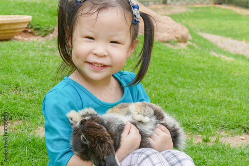Little asian girl holding rabbit in park